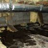 Fiberglass insulation dripping off a floor joist in a soaked crawl space with a think black liner in Binghamton.