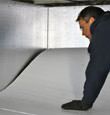 A contractor installing TerraBlock™ floor insulation in a Newfield crawl space
