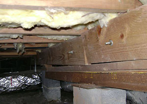 A sagging crawl space with concrete supports and wooden shimming a Pine City crawl space