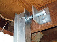 Securing the i-beam system to the top of the floor joist in a foundation wall repair in Newfield.