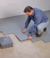 Contractors installing basement subfloor tiles and matting on a concrete basement floor in Endicott, New York