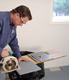 installing a waterproof vapor barrier on a basement floor to prepare for basement carpeting in a Vestal home