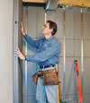 Insulated basement wall panels being placed against a concrete foundation wall in Conklin